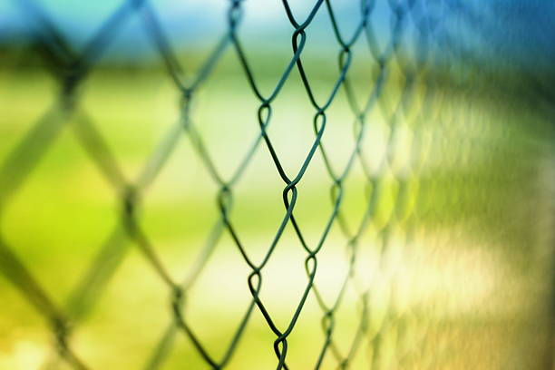 Close-up section of a chain-link fence with field behind it stock photo