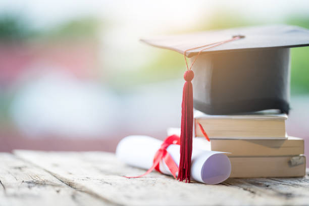 Close-up selective focus of a graduation cap or mortarboard and diploma degree certificate put on the table Close-up selective focus of a graduation cap or mortarboard and diploma degree certificate put on the table bachelor degrees stock pictures, royalty-free photos & images