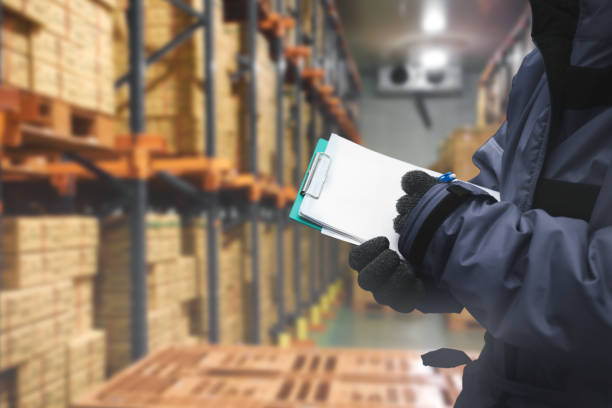 Closeup shooting hand of QC. worker checking goods on delivery in the cold room warehouse., Logistics food and beverage in cold storage concept stock photo
