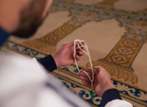 primo piano di un uomo musulmano che tiene perle di preghiera in una moschea - salah foto e immagini stock