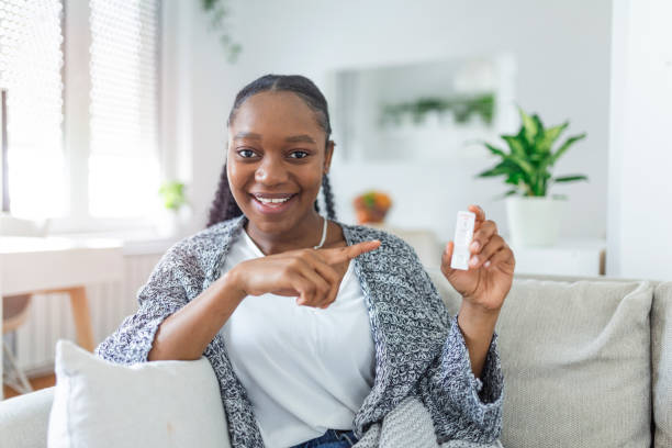 zbliżenie z afro-amerykańskiej kobiety za rękę trzymającą negatywne urządzenie testowe. szczęśliwa młoda kobieta pokazująca swój negatywny coronavirus - covid-19 szybki test. nacisk kładzie się na test. koronawirus - at home covid test zdjęcia i obrazy z banku zdjęć