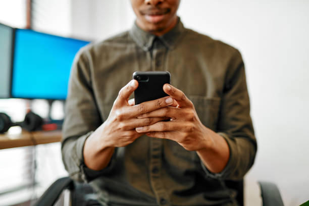 Closeup shot of an unrecognisable businessman using a cellphone in an office stock photo