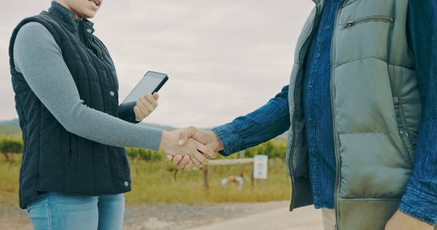 Closeup shot of an unrecognisable man and woman shaking hands on a farm stock photo