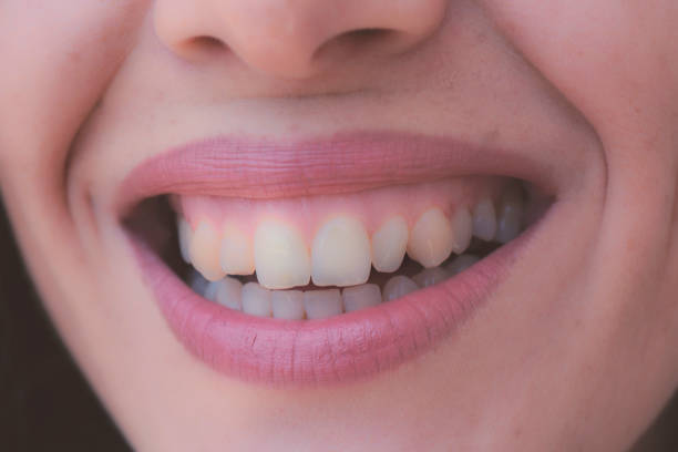 Closeup shot of human female face. Woman with pink lips and healthy dentes. Girl is smiling stock photo