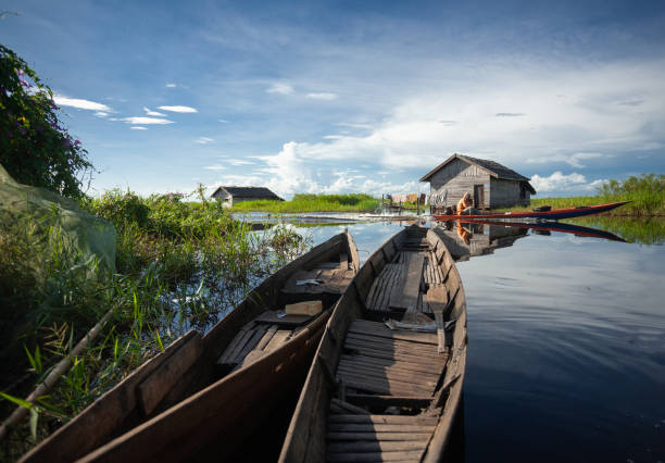closeup shot of old wooden boats in the pond with a house in the background stock photo