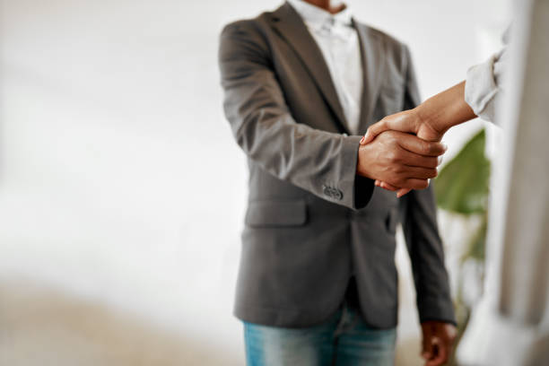 Closeup shot of two unrecognisable businesspeople shaking hands in an office stock photo