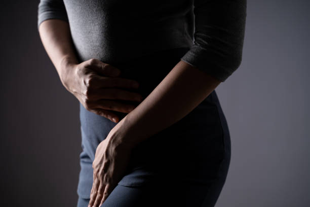 Closeup  shot of woman having painful holding hands pressing her crotch lower abdomen isolated on background. stock photo