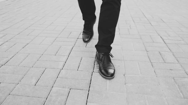 Closeup view businessman in shoes walking ahead sidewalk at street stock photo
