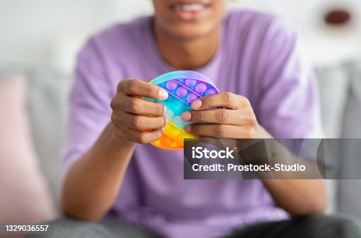 istock Closeup view of African American teenager playing with antistress POP IT toy at home 1329036557