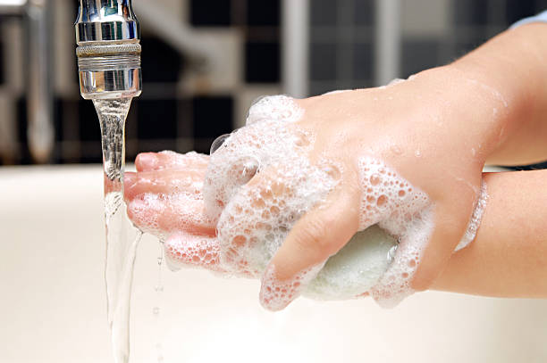 Close-up view of child scrubbing hands under faucet stock photo