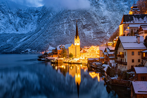 Closeup view of the famous village of Hallstatt, Austria, during winter dusk time with snow and warm lights from the houses