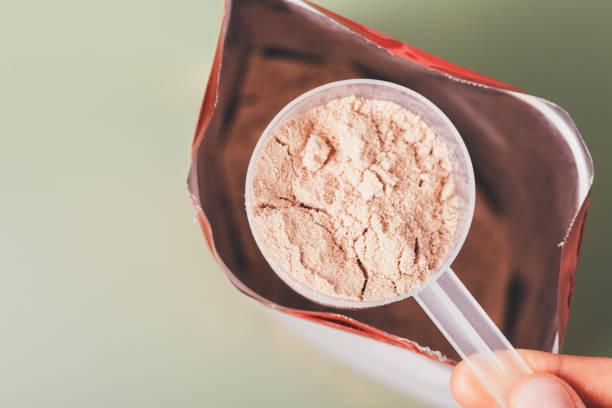 Close-up whey protein measuring spoon over open package bag stock photo