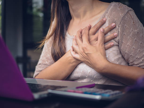 Closeup woman having heart attack. Woman touching breast and having chest pain after long hours work on computer. Office syndrome concept. stock photo