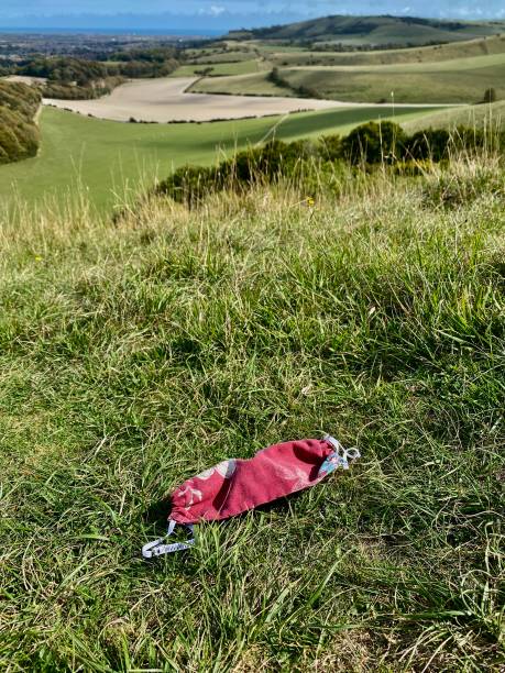 cloth face mask discarded in field during Covid-19 coronavirus pandemic stock photo