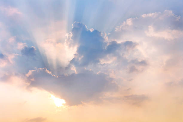 Photo of Clouds and sun shines through rays of light in the illuminated picturesque sky.