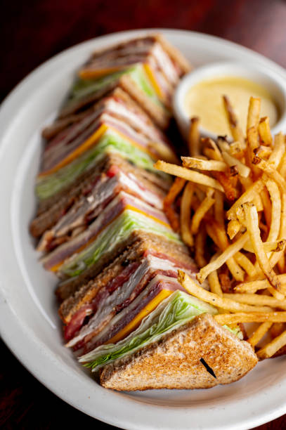 Club sandwich. BLT club sandwich. Toasted bread with Ham, turkey, bacon, melted Swiss & cheddar cheeses, bacon, sautéed onions, lettuce, tomato, mayo, salt & pepper. Classic lunch sandwich favorite. stock photo