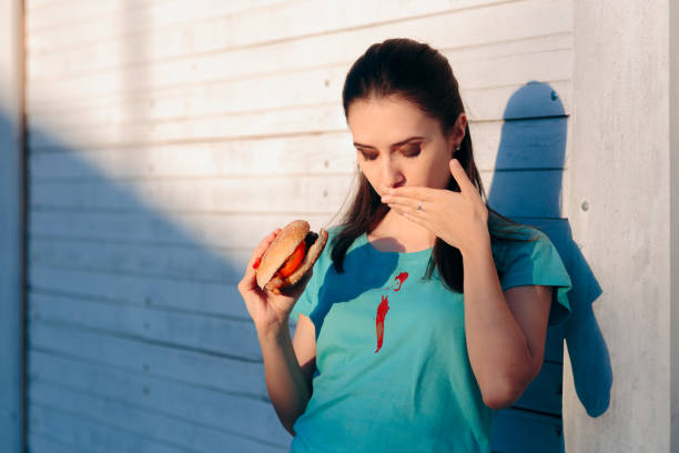 Clumsy Woman Staining Her Shirt with Ketchup Sauce Lady ruining her t-shirt with tomato sauce eating burger ketchup smear stock pictures, royalty-free photos & images