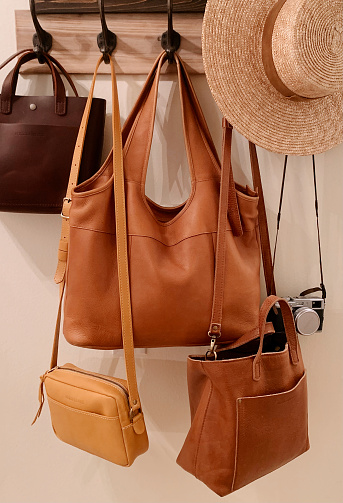 Coat Hooks with Full Grain Leather Purses & a Straw Boater Hat.
