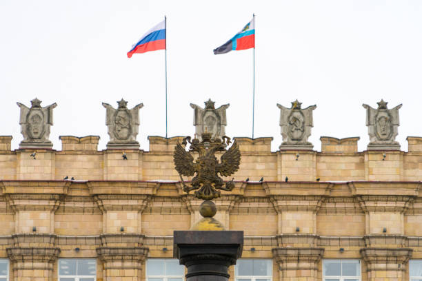 герб россии на фоне здания с флагами. - belgorod стоковые фото и изображения