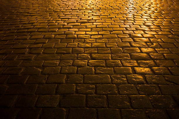 cobbled road close-up of a cobbled road in the city light, at night cobblestone stock pictures, royalty-free photos & images