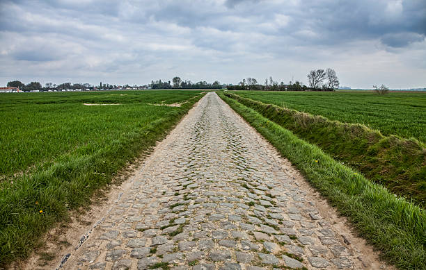 Cobbled Road Cobbelstone road located in the North of France near Lille. On such roads every year is organized one of the most famous one day cycling race Paris-Roubaix. cobblestone stock pictures, royalty-free photos & images