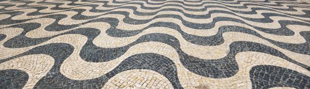 Cobblestone road close-up. Black and white wave pattern. Texture, background, wallpaper. Cascais, Lisbon District, Portugal. Travel, tourism, walking, cycling. Details of urban design. Panoramic view stock photo