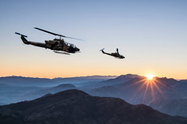 AH-1 Cobra Attack helicopters flying over mountains at sunrise AH-1 Cobra Attack helicopters flying over mountains at sunrise military helicopter stock pictures, royalty-free photos & images