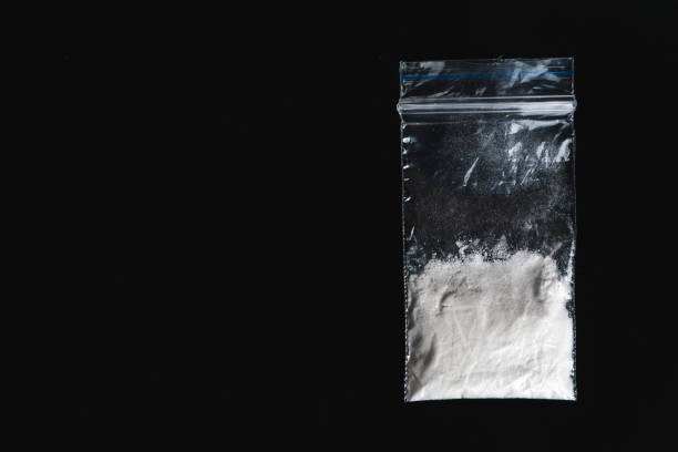 Cocaine in plastic packet on black background, closeup. Portion of drugs. Cocaine in plastic packet on black background, closeup. Portion of drugs. Top view with copy space heroin stock pictures, royalty-free photos & images
