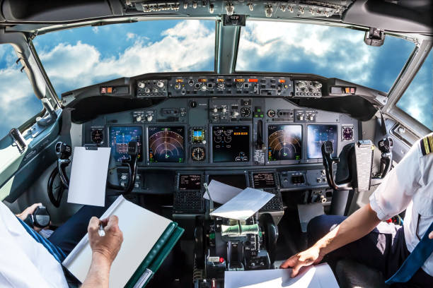 Cockpit in cloudy sky Airplane cockpit flying in a cloudy blue sky at day. with pilots arms and blank white papers for copy space. cockpit stock pictures, royalty-free photos & images