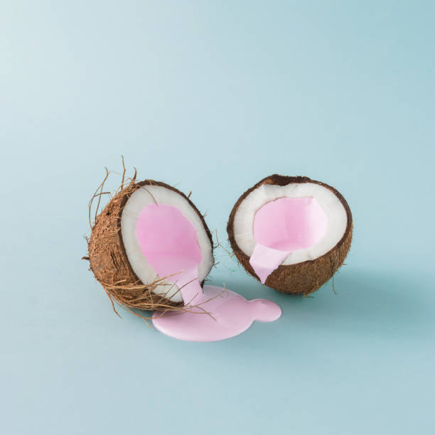 Coconut cracked in half with pink milk pouring. Minimalism. Food creative concept. Coconut cracked in half with pink milk pouring. Minimalism. Food creative concept. simplicity photos stock pictures, royalty-free photos & images