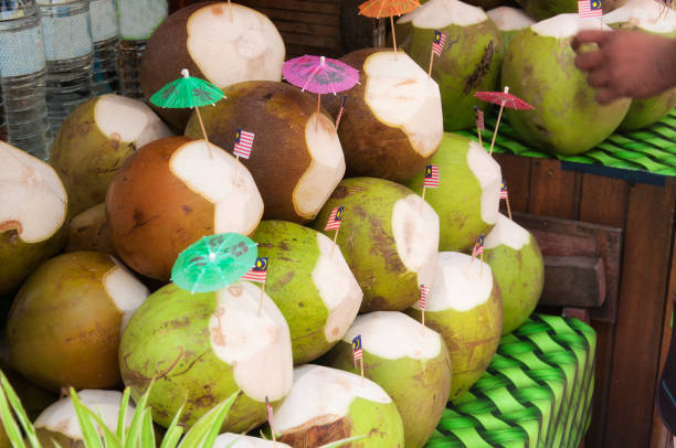 Coconut drink stand kuala lumpur malaysia Coconut drinks with the malaysian flag and umbrella for sale in a market within the kasturi walk shopping area in kuala lumpur malaysia. central market kuala lumpur stock pictures, royalty-free photos & images