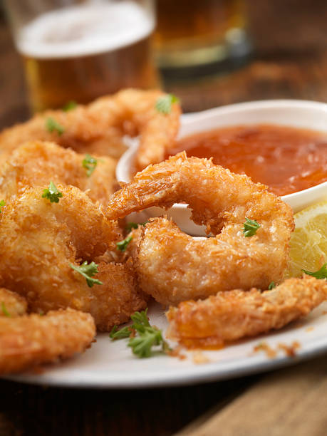 Coconut Shrimp Coconut Jumbo Shrimp with fresh Parsley, Lemon, Dipping Sauce and a couple of beers - Photographed on Hasselblad H3D2-39mb Camera cocktail sauce stock pictures, royalty-free photos & images