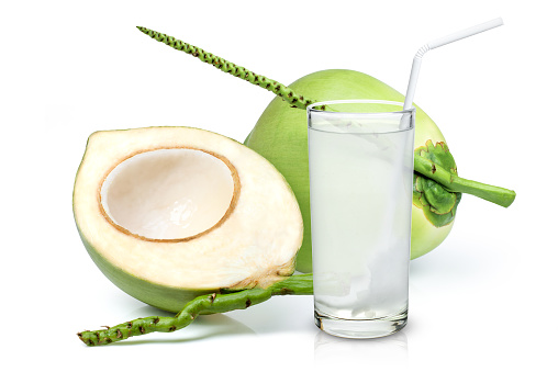 Glass of coconut juice with straw and young green coconut fruit isolated on white background.