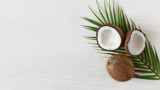 Coconuts with palm leaf on white wooden background. Tropical fruit.