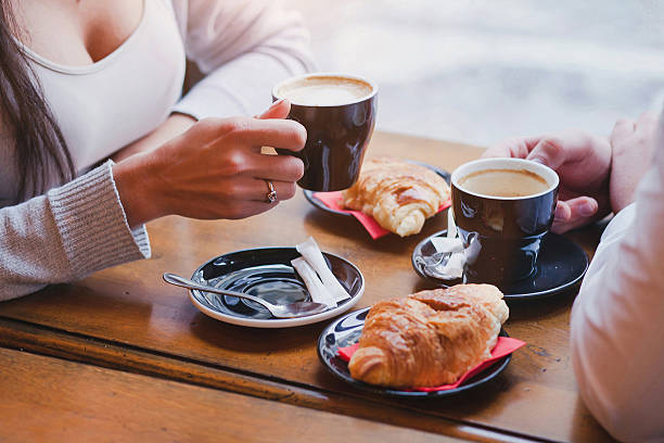coffee and croissants in cafe, couple having breakfast coffee and croissants in cafe, hands of couple closeup couple eating chocolate stock pictures, royalty-free photos & images