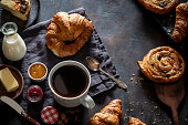 Coffee breakfast with pastries croissants, butter, cheesecake homemade on dark background