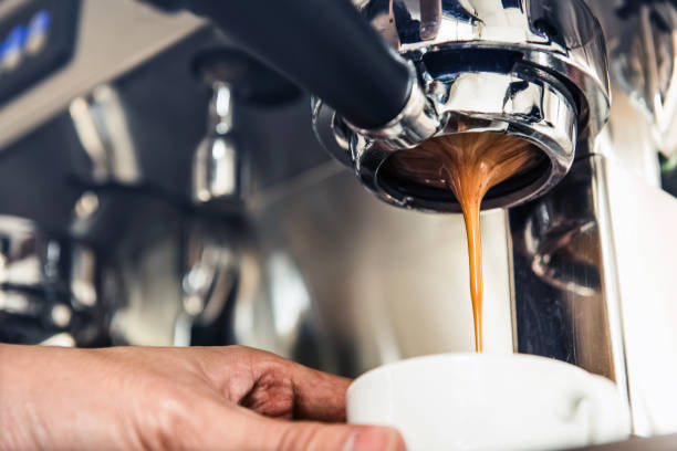koffie druipend uit de machine in de beker - espresso stockfoto's en -beelden