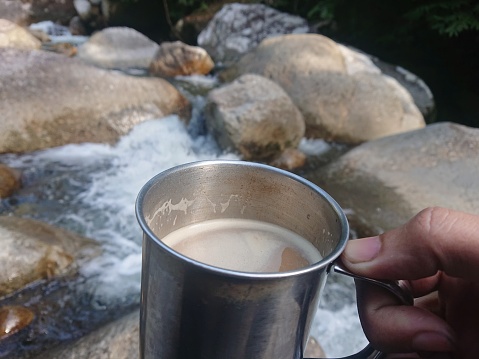 coffee in the metal cup with river background
