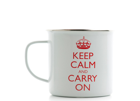 London, England-March 29, 2011.  White metal coffee mug with the famous British saying Keep Calm and Carry On written on it.  Mug is on a white background.