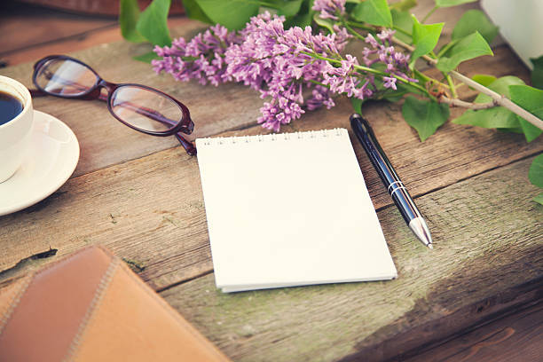 .cup of coffee, pen, notepad, papers, glasses and flower on wooden...