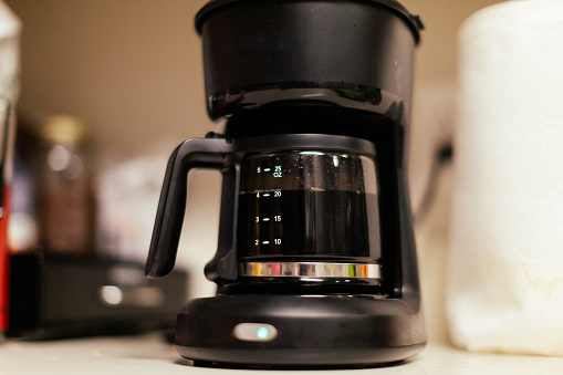 A coffee pot in a residential kitchen warm with hot coffee.