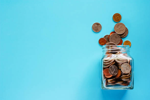 munten in glazen pot en buiten, thaise munt geld op blauwe achtergrond voor business en finance concept - glazen pot stockfoto's en -beelden