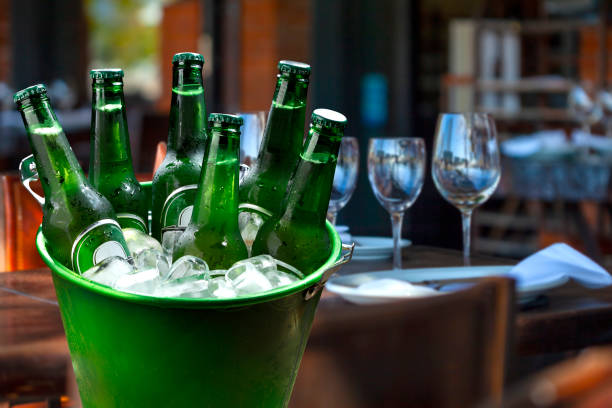 cold bottles of beer in bucket with ice in a restaurant setting stock photo