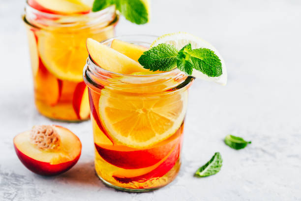 Cold peach and lemon iced tea. Summer refreshing drink Cold peach and lemon iced tea. Summer refreshing drink with peach, lemon and ice. infused photos stock pictures, royalty-free photos & images