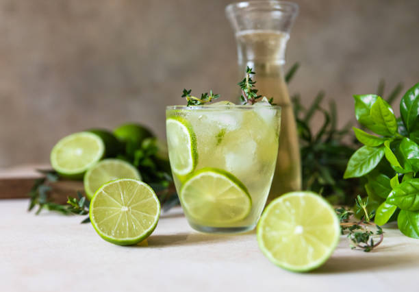 Cold refreshing summer drink or lemonade with lime and thyme on concrete background. stock photo