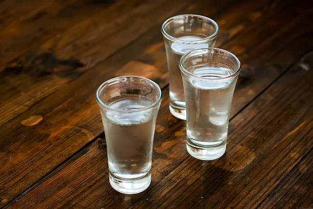 Cold vodka in a glass on a wooden table tru misted glasses with cold water on an old wooden table vodka stock pictures, royalty-free photos & images
