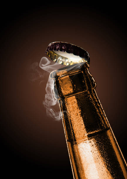 Cold wet bottle of chilled drink with drops. Opening of beer cap with the gas output. stock photo
