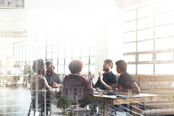 Collaborating to build the city of their dreams Multiple exposure shot of businesspeople having a meeting superimposed over a cityscape business meeting photos stock pictures, royalty-free photos & images