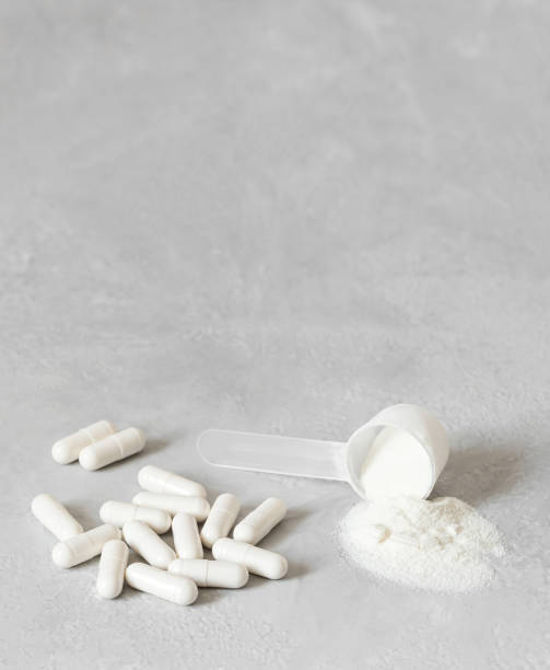 Collagen powder and pills on a gray background. Natural health and beauty supplement for bones, joints and skin. Vertical orientation. Copy space stock photo