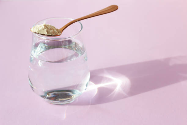 Collagen powder in a spoon and a glass of water on a pink background. Beauty concept. Place for your text Collagen powder in a spoon and a glass of water on a pink background. Beauty concept. Place for your text. collagen stock pictures, royalty-free photos & images